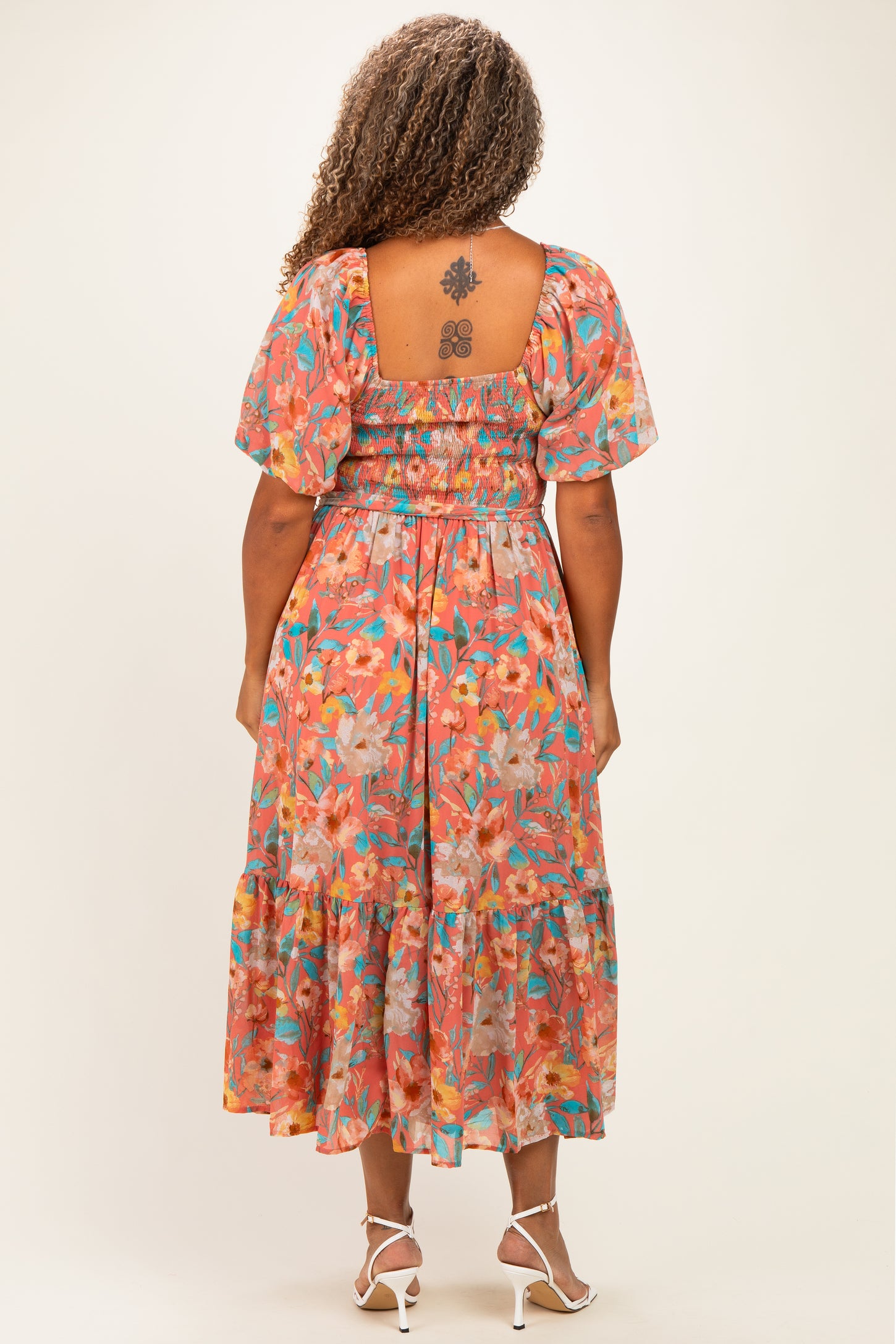 woman wearing a floral printed plus-size midi dress with puff sleeves and a smocked bodice, showing a tiered skirt