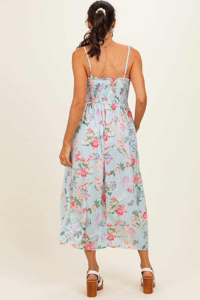 woman wearing a floral smocked midi dress with thin straps and a flowy skirt, view from the back