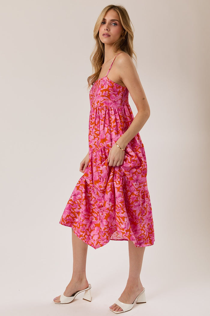 woman wearing a pink floral midi dress with adjustable straps and a flowy skirt