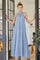 woman wearing a light blue halter neck maxi dress standing in a doorway with her hands on the door frame