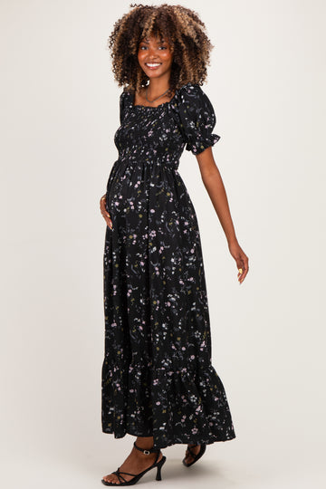 woman wearing a black floral maternity maxi dress with puff sleeves and a visible baby bump