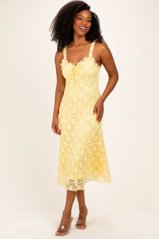woman wearing a light yellow lace midi dress with thick straps and a bow tie detail at the bust