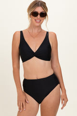 woman wearing a black bikini with a twist front top and high-waisted bottom, accessorized with sunglasses