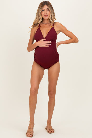 woman wearing a burgundy ribbed maternity swimsuit with adjustable straps and a visible baby bump