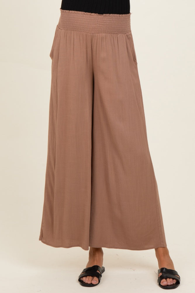 woman wearing light brown wide leg maternity pants with a smocked waistband and pockets