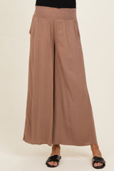 woman wearing light brown wide leg maternity pants with a smocked waistband and pockets