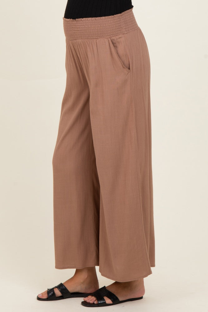 woman wearing light brown wide-leg maternity pants with a smocked waistband and side pockets