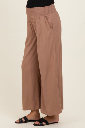 woman wearing light brown wide-leg maternity pants with a smocked waistband and side pockets