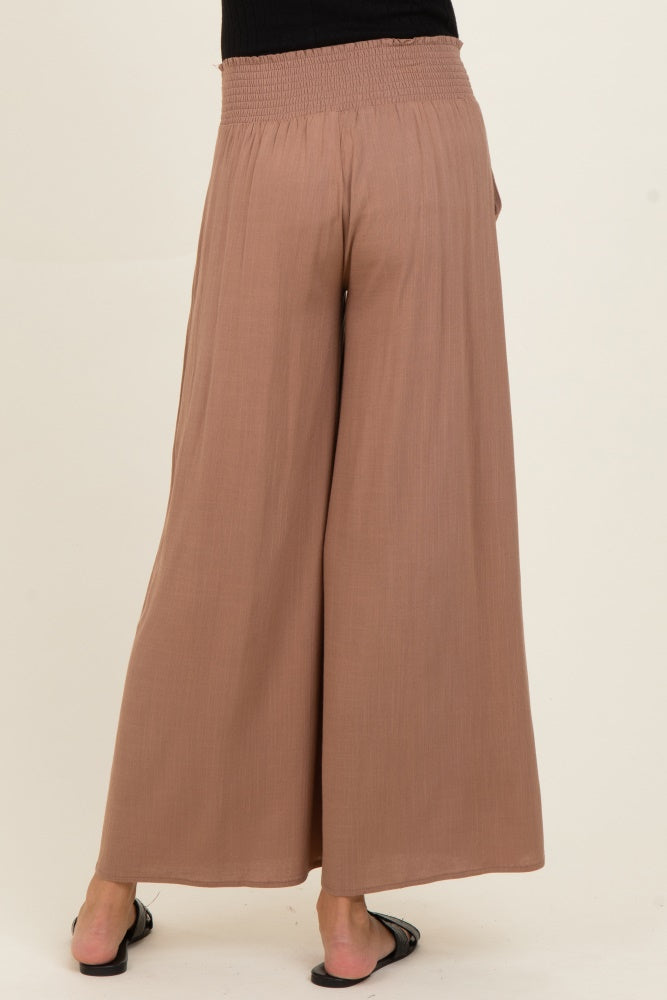 woman wearing light brown maternity wide-leg pants with a smocked waistband, view from the back
