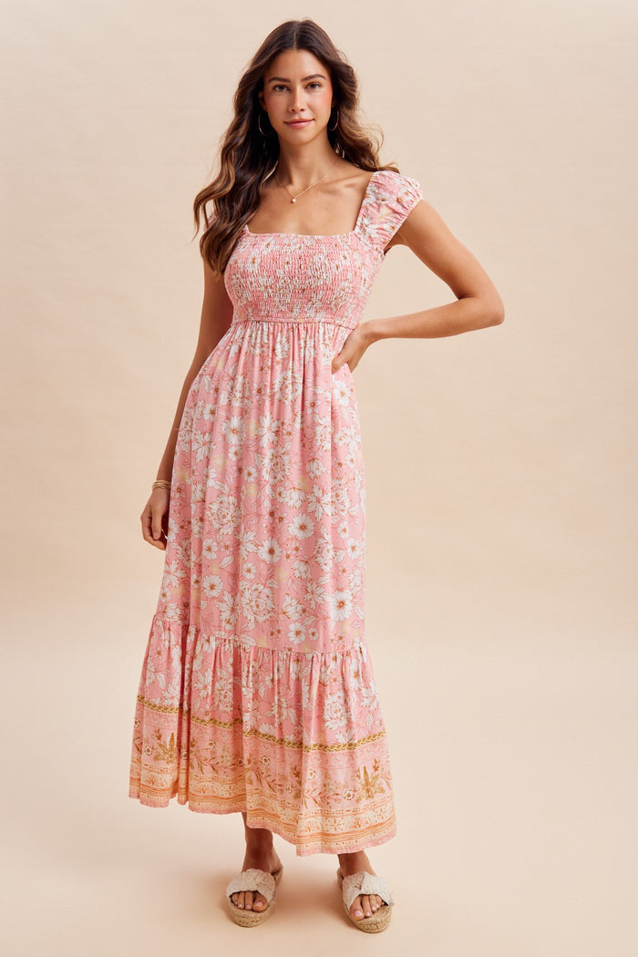 woman wearing a pink floral maxi dress with smocked bodice and ruffled sleeves
