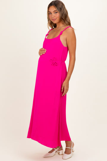 woman wearing a bright pink maternity dress with a tie detail at the waist and holding her baby bump