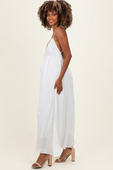 woman wearing a white maternity maxi dress with a deep v-neck and flowing skirt, showcasing her baby bump