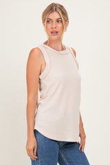 woman wearing a beige sleeveless ribbed top paired with blue jeans