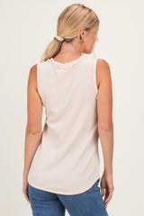woman wearing a light beige sleeveless ribbed top, seen from the back, paired with blue jeans