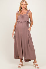 woman wearing a mauve maternity jumpsuit with ruffled straps and pockets, showing her baby bump