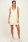 woman wearing a light yellow sleeveless dress with pockets and white sneakers
