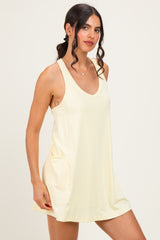 woman wearing a pale yellow sleeveless dress with a scoop neckline and side pockets