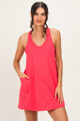 woman wearing a bright pink sleeveless dress with a v-neck and side pockets