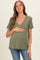 woman wearing an olive green short sleeve maternity top and holding her baby bump