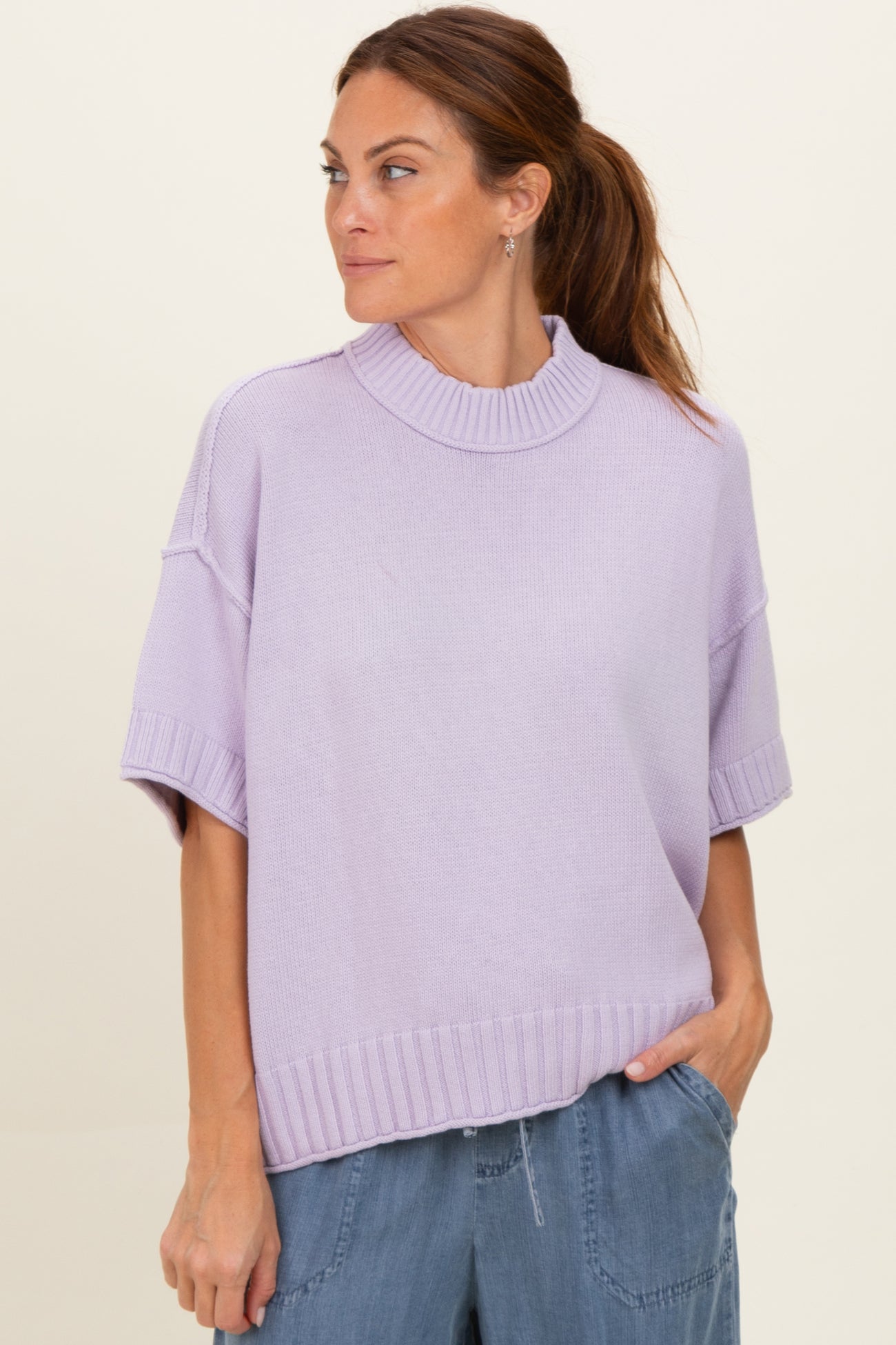 woman wearing a lavender oversized short sleeve sweater with a high neckline, paired with light blue pants