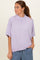 woman wearing a lavender oversized short sleeve sweater with a high neckline, paired with light blue pants