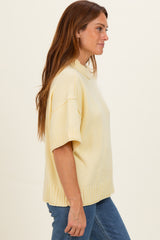 woman wearing a light yellow short sleeve casual sweater with a relaxed fit and ribbed hem, styled with blue jeans