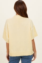 woman wearing a light yellow oversized sweater with ribbed hem and short sleeves, viewed from the back