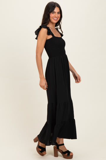 woman wearing a black maxi dress with ruffled straps and a tiered skirt, paired with platform heels