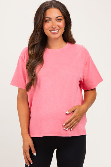 woman wearing a pink short sleeve maternity top and cradling her baby bump