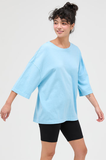 woman wearing a light blue oversized t-shirt with wide sleeves and black bike shorts while walking