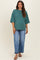 woman wearing a green oversized maternity t-shirt with short sleeves and blue wide-leg jeans