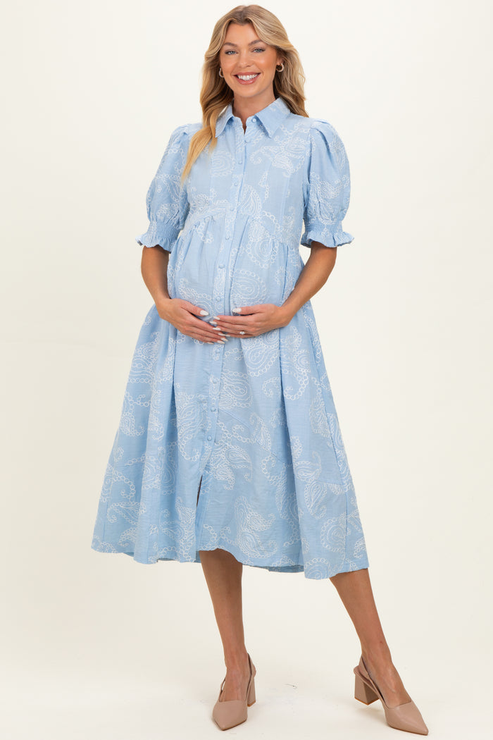 woman wearing a light blue button-up maternity dress with puff sleeves and a visible baby bump
