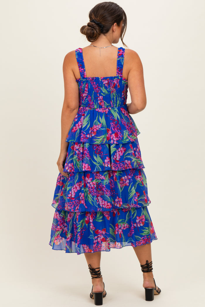woman wearing a blue floral tiered maternity dress, showing the back with smocked bodice and ruffled layers