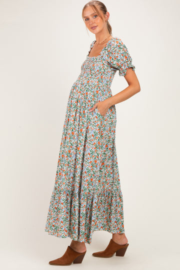 woman wearing a floral print maternity maxi dress with puff sleeves and pockets, showing her baby bump