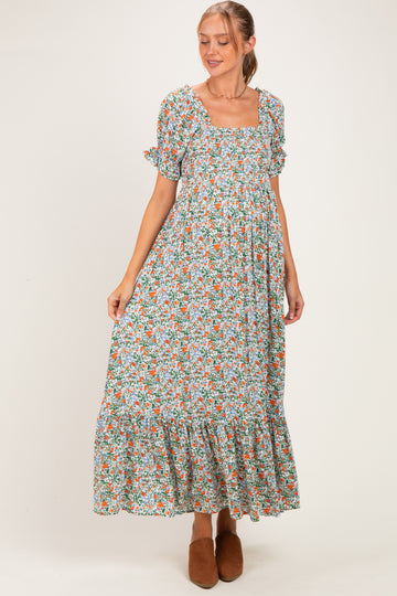 woman wearing a floral maxi maternity dress with short sleeves and a square neckline, showing her baby bump