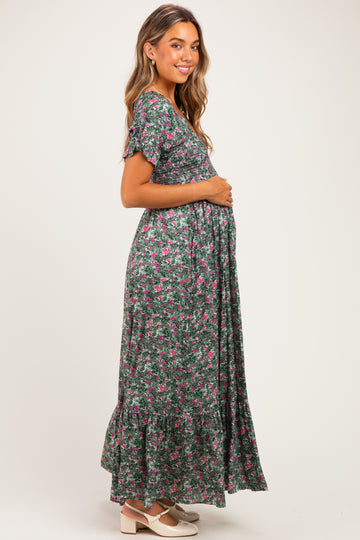 woman wearing a green floral maternity maxi dress and holding her baby bump