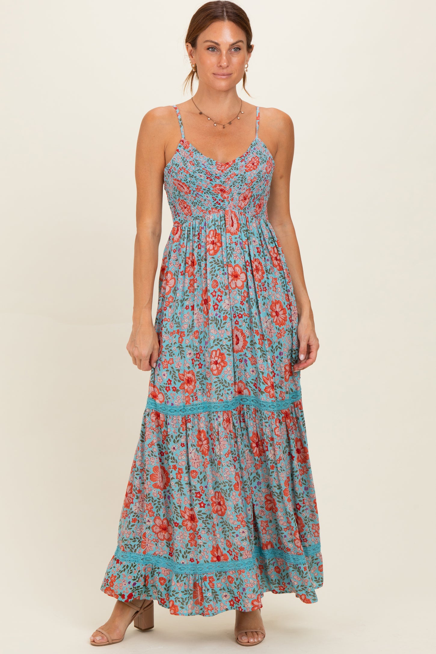 woman wearing a floral print maxi dress in blue with red and orange flowers and adjustable spaghetti straps