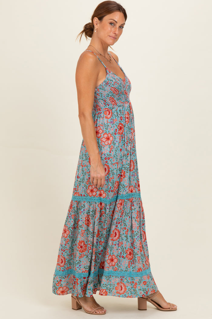 woman wearing a blue floral maxi dress with spaghetti straps and a tiered skirt