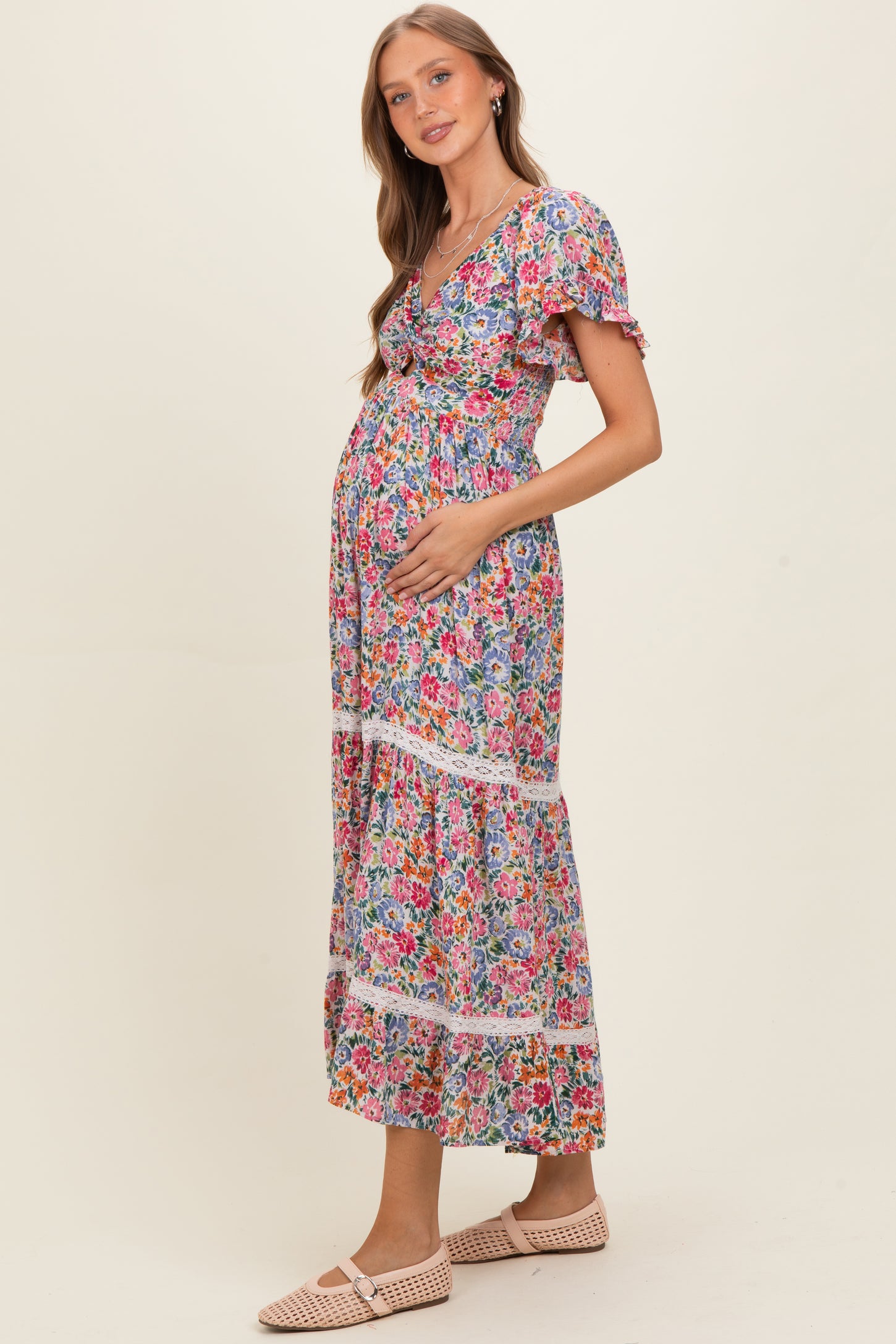 woman wearing a colorful floral maternity maxi dress and holding her baby bump