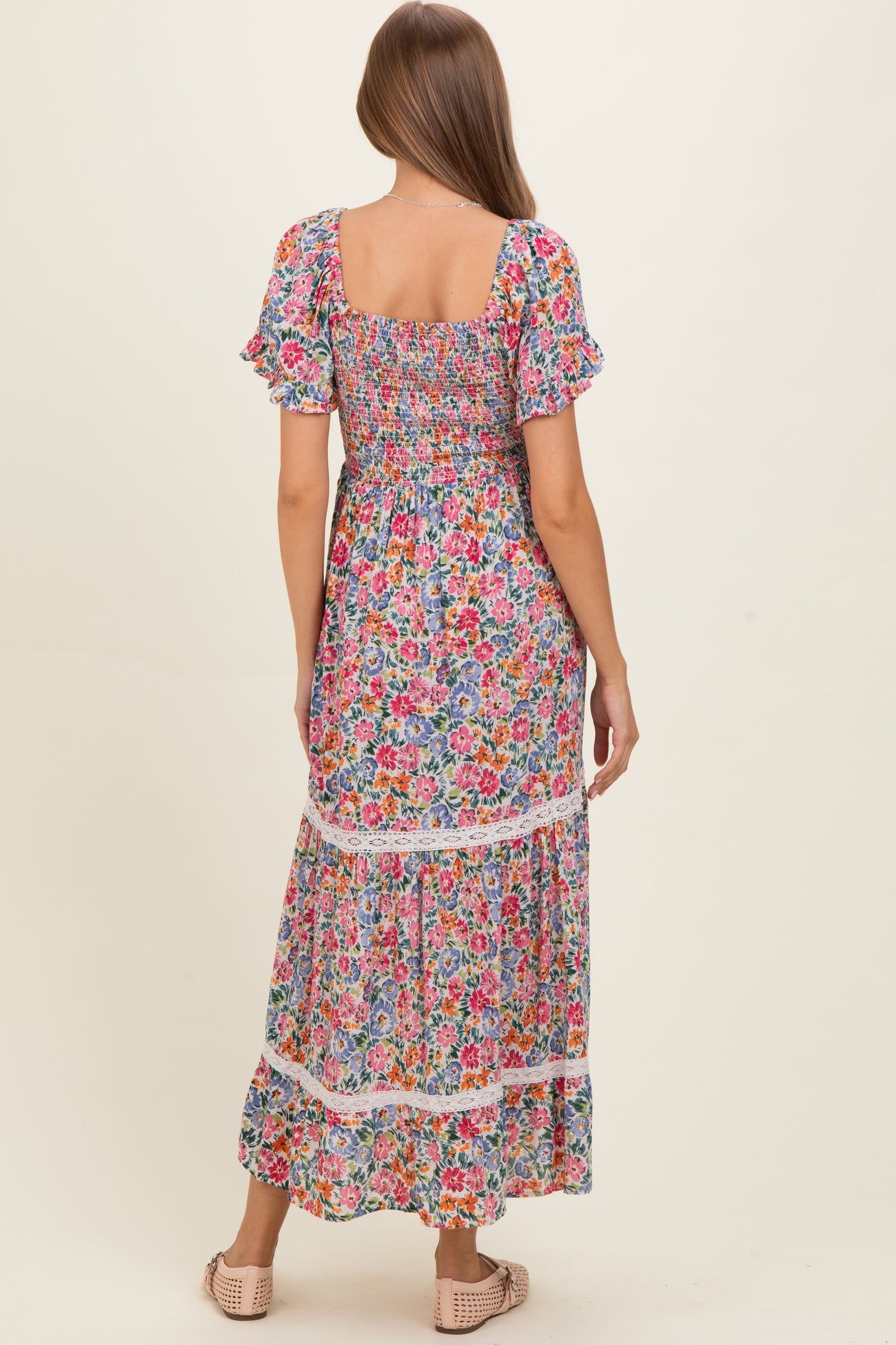 woman wearing a floral maxi maternity dress with short puff sleeves and a smocked bodice, showing a baby bump