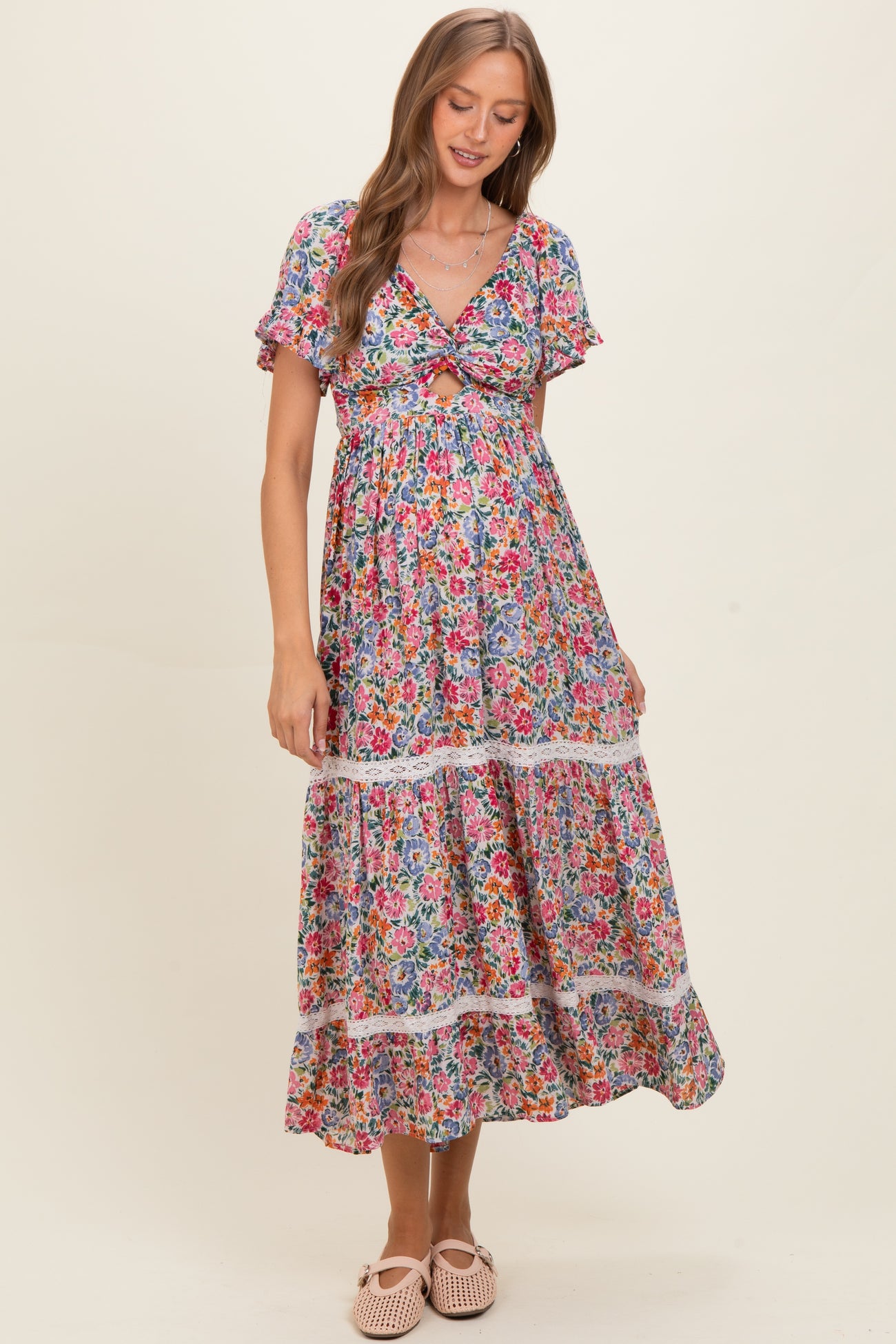 woman wearing a floral print maternity dress with short flutter sleeves and a tie front, showcasing a baby bump