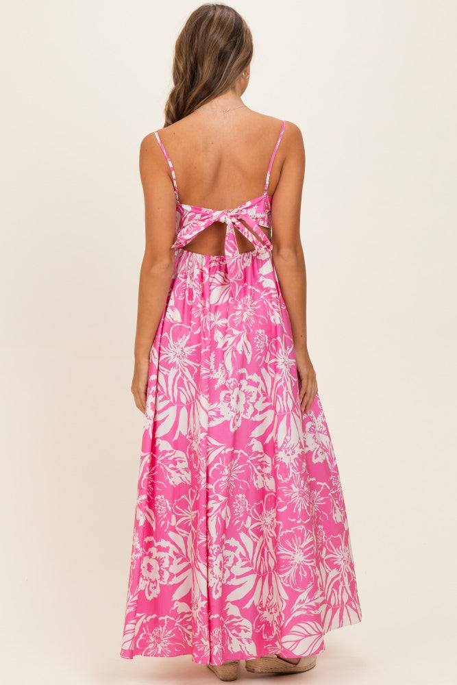 woman wearing a pink floral maxi dress with a tie-back detail and a flowy silhouette