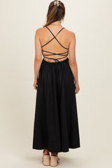 woman wearing a black maternity dress with a crisscross back and a flowy skirt, showing a baby bump