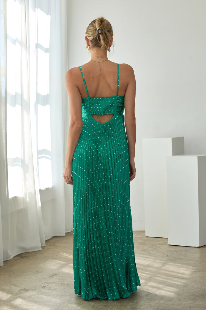 woman wearing a green spaghetti strap maxi dress with a cutout back and pleated design