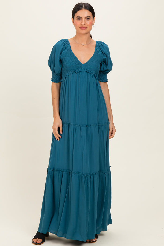 woman wearing a teal puff sleeve maxi dress with a deep v-neck and tiered skirt