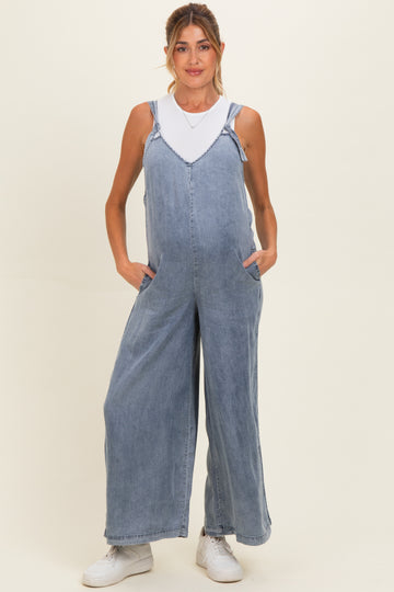 woman wearing a light wash denim maternity overall with wide legs and pockets, showcasing her baby bump