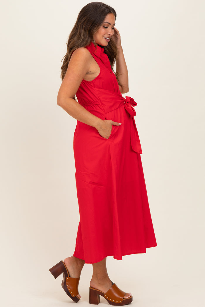 woman wearing a bright red maternity dress with a tie waist and pockets, smiling while touching her hair