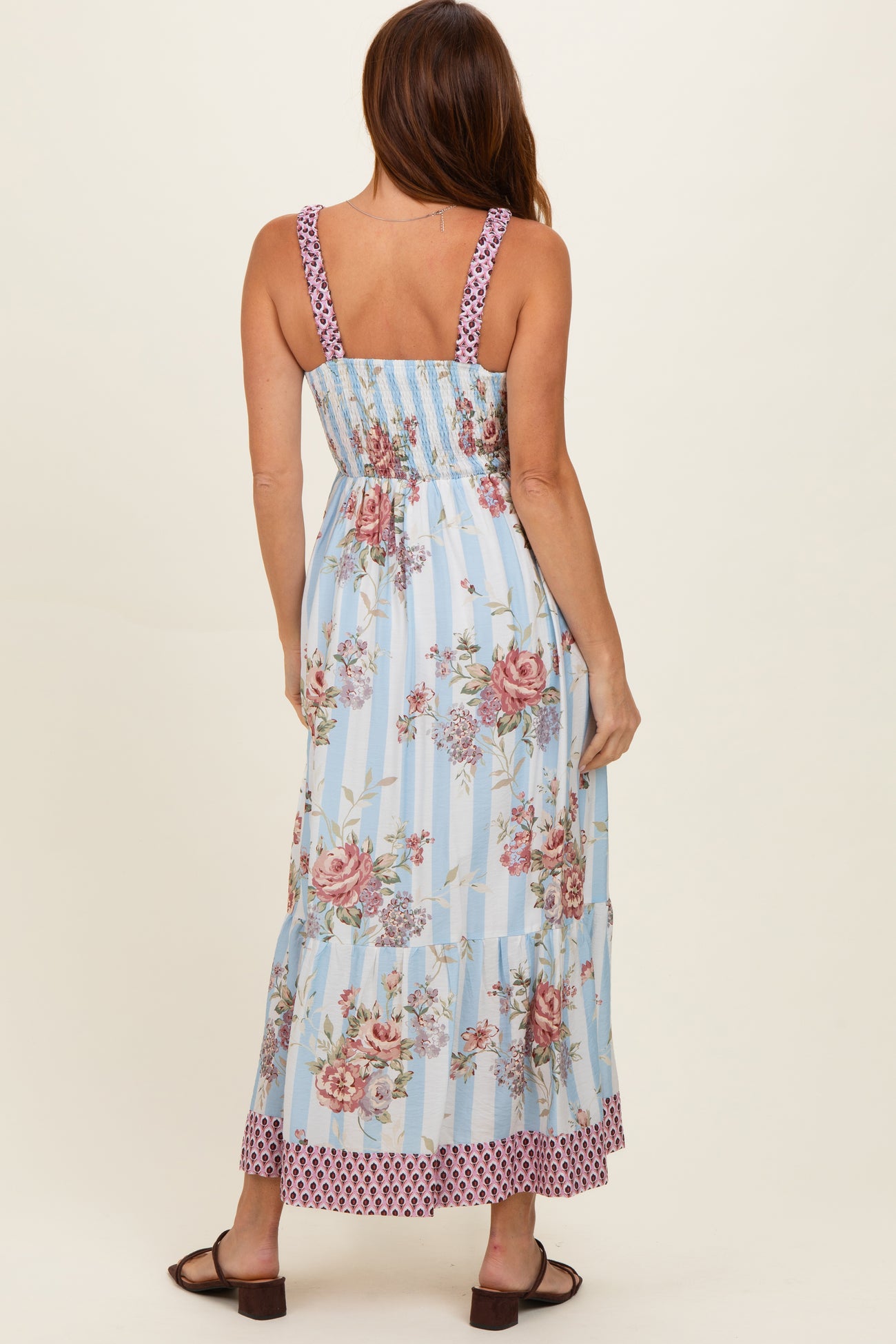 woman wearing a light blue floral maxi dress with smocked bodice and tiered skirt, viewed from the back