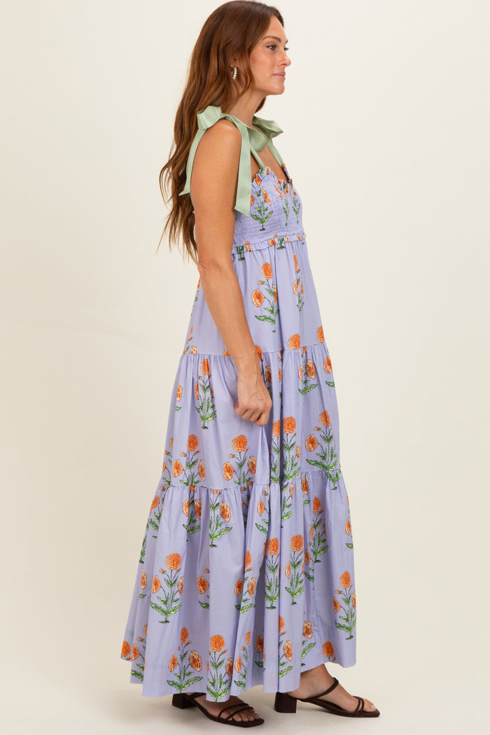 woman wearing a lavender floral maxi dress with green tie straps and a tiered skirt