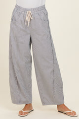 woman wearing gray and white striped wide-leg pants with an elastic waistband and drawstring, styled with flat sandals